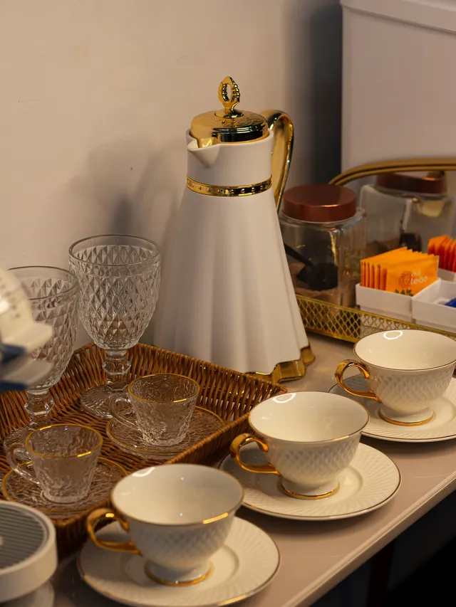 Jarra branca com detalhes dourados e xícaras de porcelana